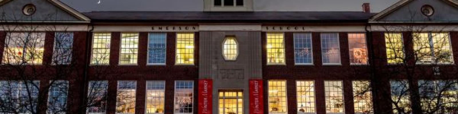Brick building at night with holiday lights in windows